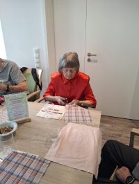 Seniorin bastelt in der Tagespflege Leipzig-Stötteritz mit Stoffen und Kräutern ein Duftsäckchen.