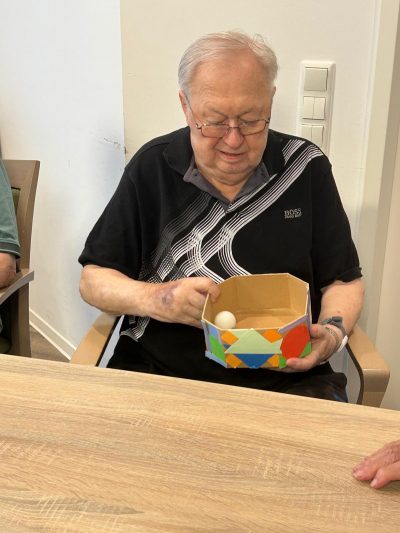 Senior mit Bastelarbeit und Ballspiel in der Tagespflege Leipzig.