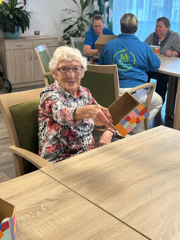 Seniorin zeigt stolz ihre Bastelarbeit in der Tagespflege Leipzig-Stötteritz.