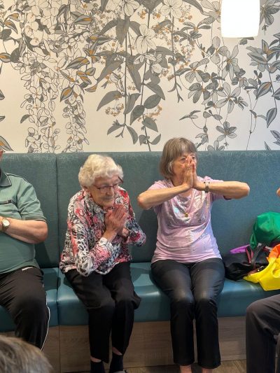 Seniorinnen machen Bewegungsübungen im Sitzen in der Tagespflege Leipzig.