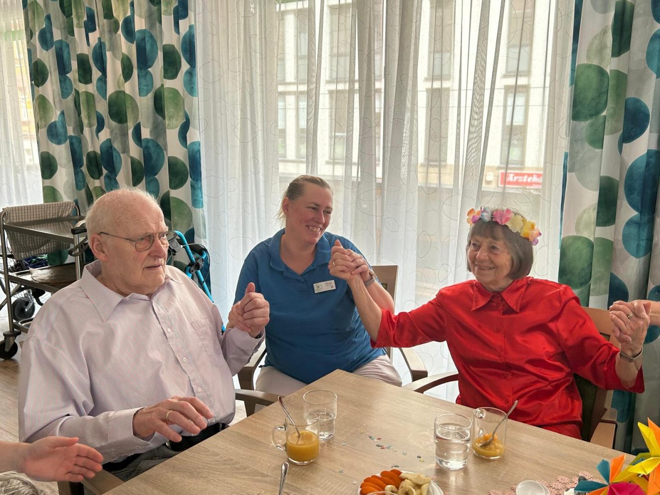 Senioren und Pflegekraft tanzen und halten Hände beim Sommerfest Leipzig-Stötteritz.