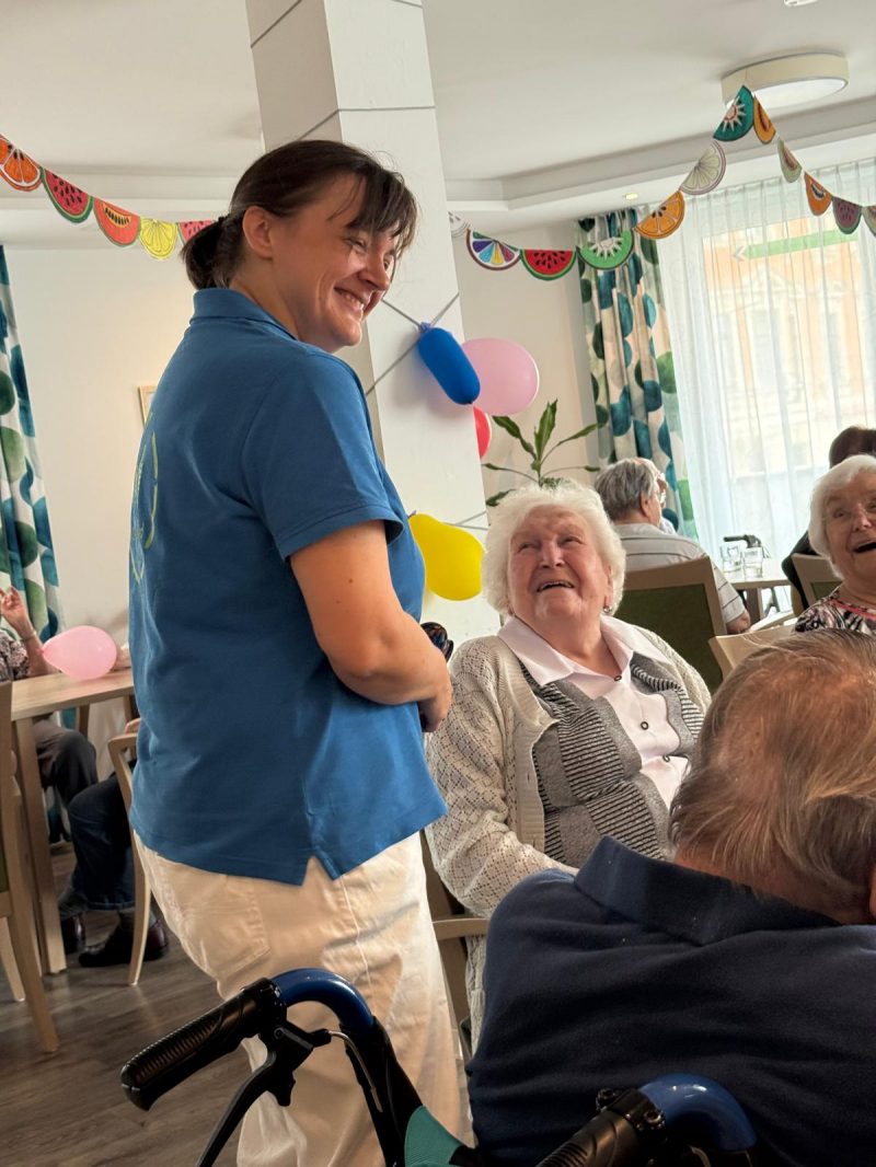 Pflegekraft im Gespräch mit Seniorin beim Sommerfest der Tagespflege Leipzig-Stötteritz.