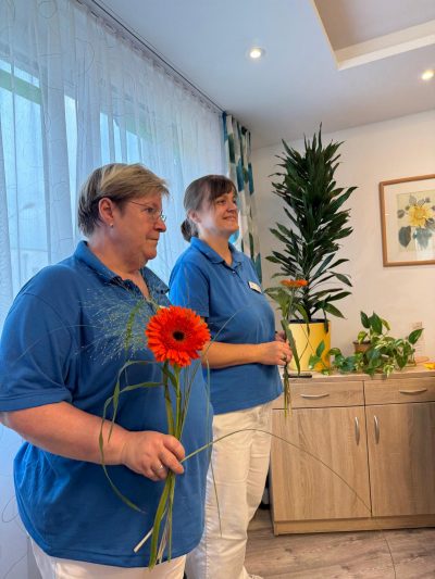 Pflegekräfte halten Blumen in der Hand beim Sommerfest der Tagespflege Leipzig.