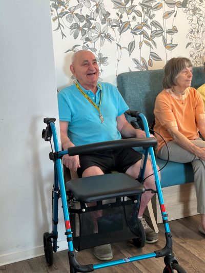 Lachender Senior mit Rollator beim Sommerfest in der Tagespflege Leipzig-Stötteritz.