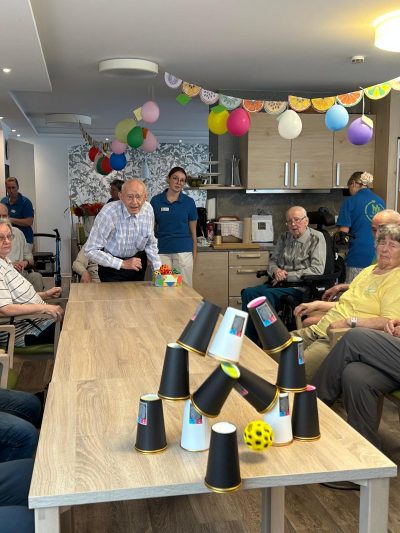 Senior wirft Ball auf Becherpyramide beim Sommerfest in Leipzig-Stötteritz.