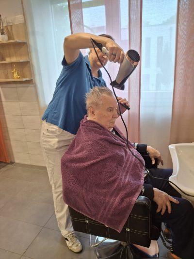 Senior erhält liebevolle Haarpflege im Friseurbereich der Tagespflege Leipzig-Stötteritz