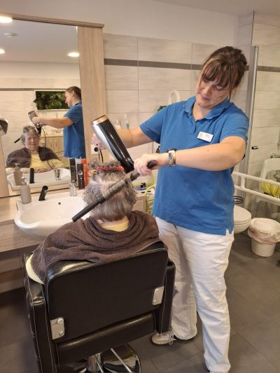 Seniorin beim Haareföhnen im Friseurraum der Tagespflege Leipzig-Stötteritz