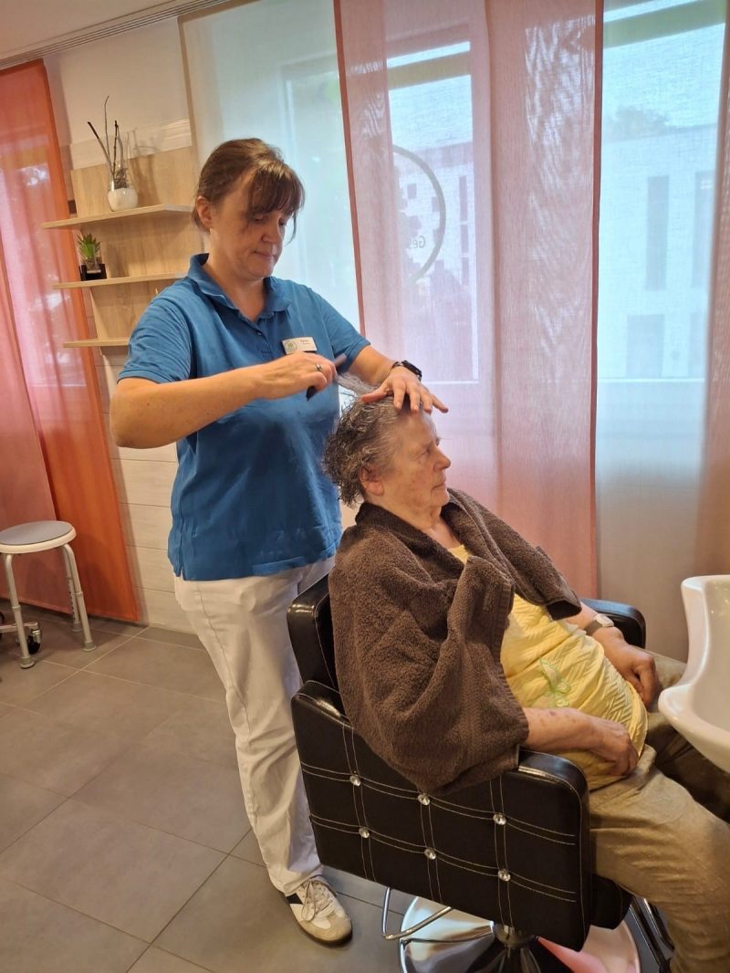 Seniorin bekommt Frisurpflege im Friseurraum der Tagespflege Leipzig