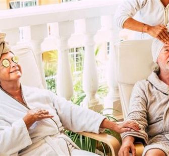 Senior erhält Gesichtsmassage in Tagespflege-Wellnesswoche, entspannt und glücklich