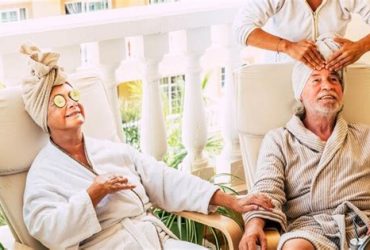 Senior erhält Gesichtsmassage in Tagespflege-Wellnesswoche, entspannt und glücklich