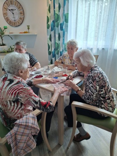 Seniorinnen sitzen am Tisch und schneiden Stoff für Lavendel- und Rosenduftsäckchen in Leipzig-Stötteritz.