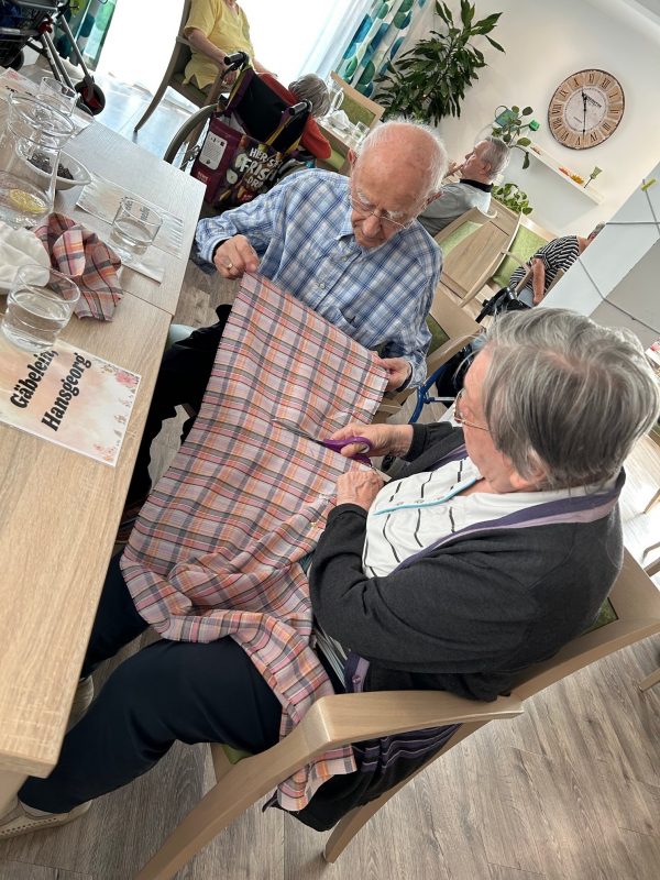 Seniorenpaar arbeitet zusammen beim Basteln von Duftsäckchen in der Tagespflege Leipzig-Stötteritz.