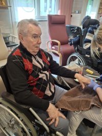 Senior im Rollstuhl lächelt nach Handpflege in der Tagespflege Leipzig.