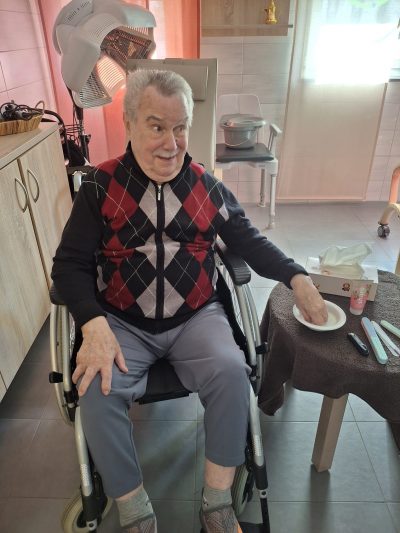 Senior im Rollstuhl lächelt zufrieden nach Handpflege in der Tagespflege Leipzig-Stötteritz.