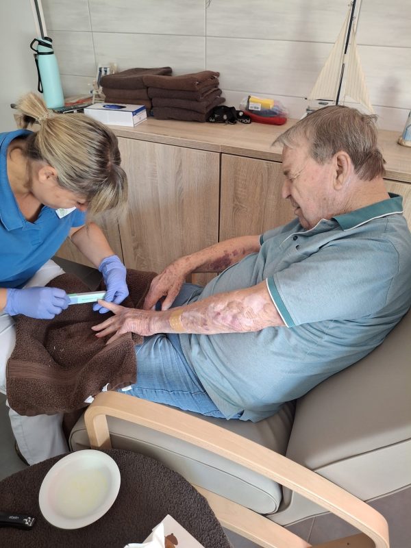 Pflegekraft feilt Nägel eines älteren Herren im Betreuten Wohnen Leipzig.