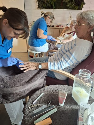 Seniorin erhält liebevolle Maniküre von Pflegekraft in der Tagespflege Leipzig-Stötteritz.
