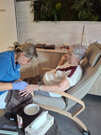 Ältere Dame entspannt bei Handpflege durch Pflegekraft im Betreuten Wohnen Leipzig.